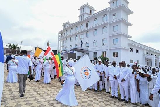 Fidèles harristes vêtus de blanc, avec drapeaux et bannières, rassemblés devant le siège mondial à Bingerville